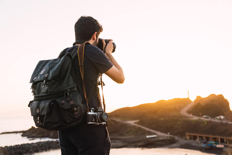 Man with Vintage Camera and Travel Backpack at Sunset